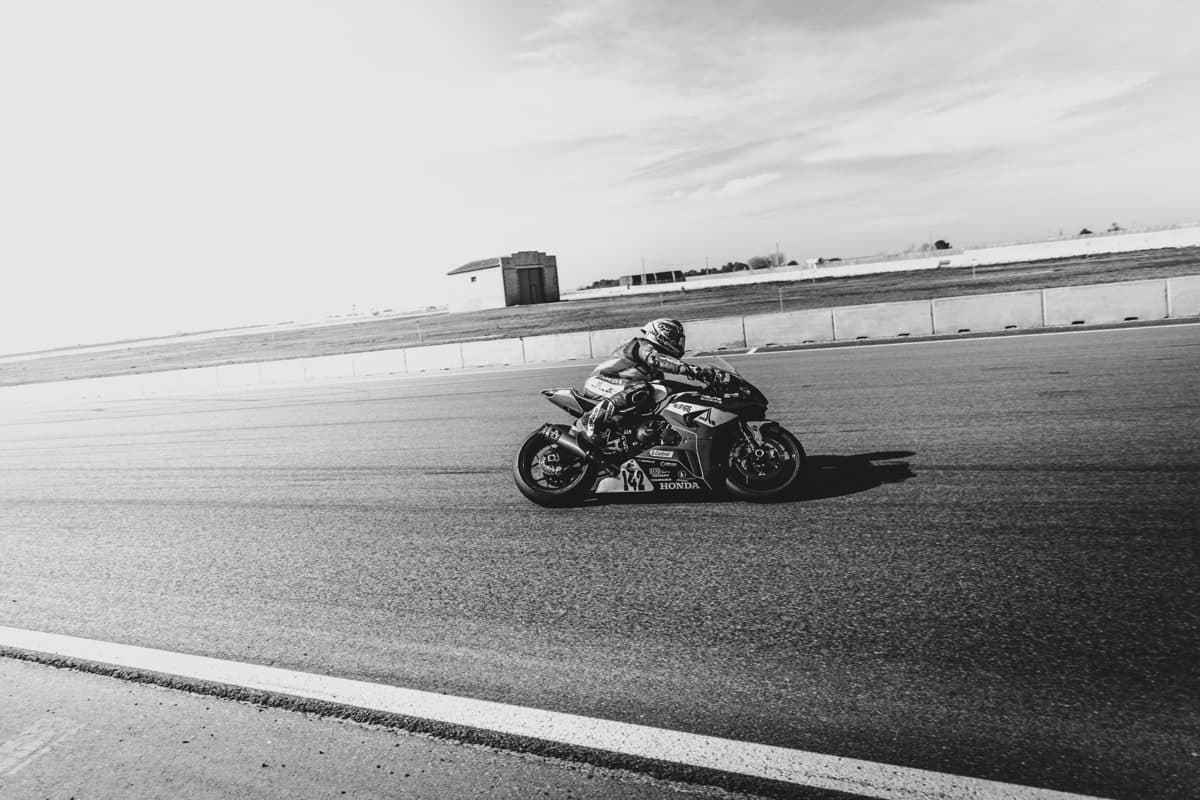 Moto sportive lancée en ligne droite sur un circuit, photo en noir et blanc