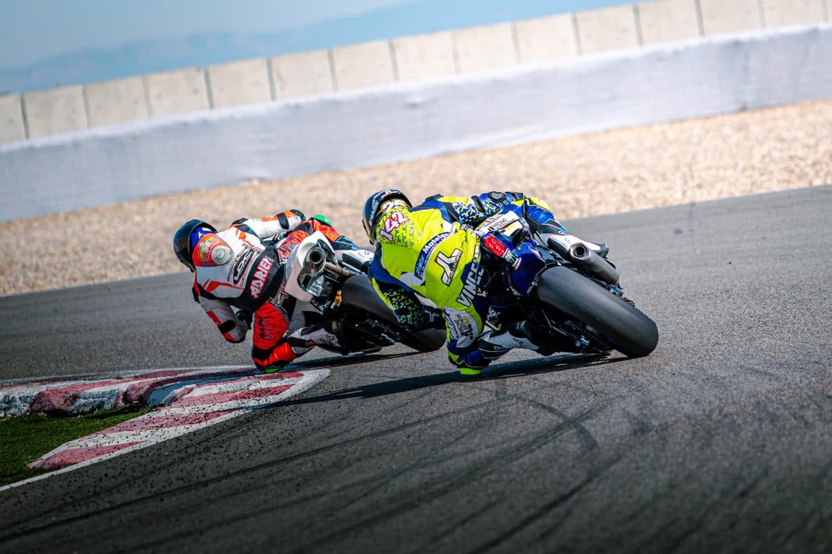 Deux pilotes enchaînent un virage en file sur circuit pendant un stage de pilotage moto