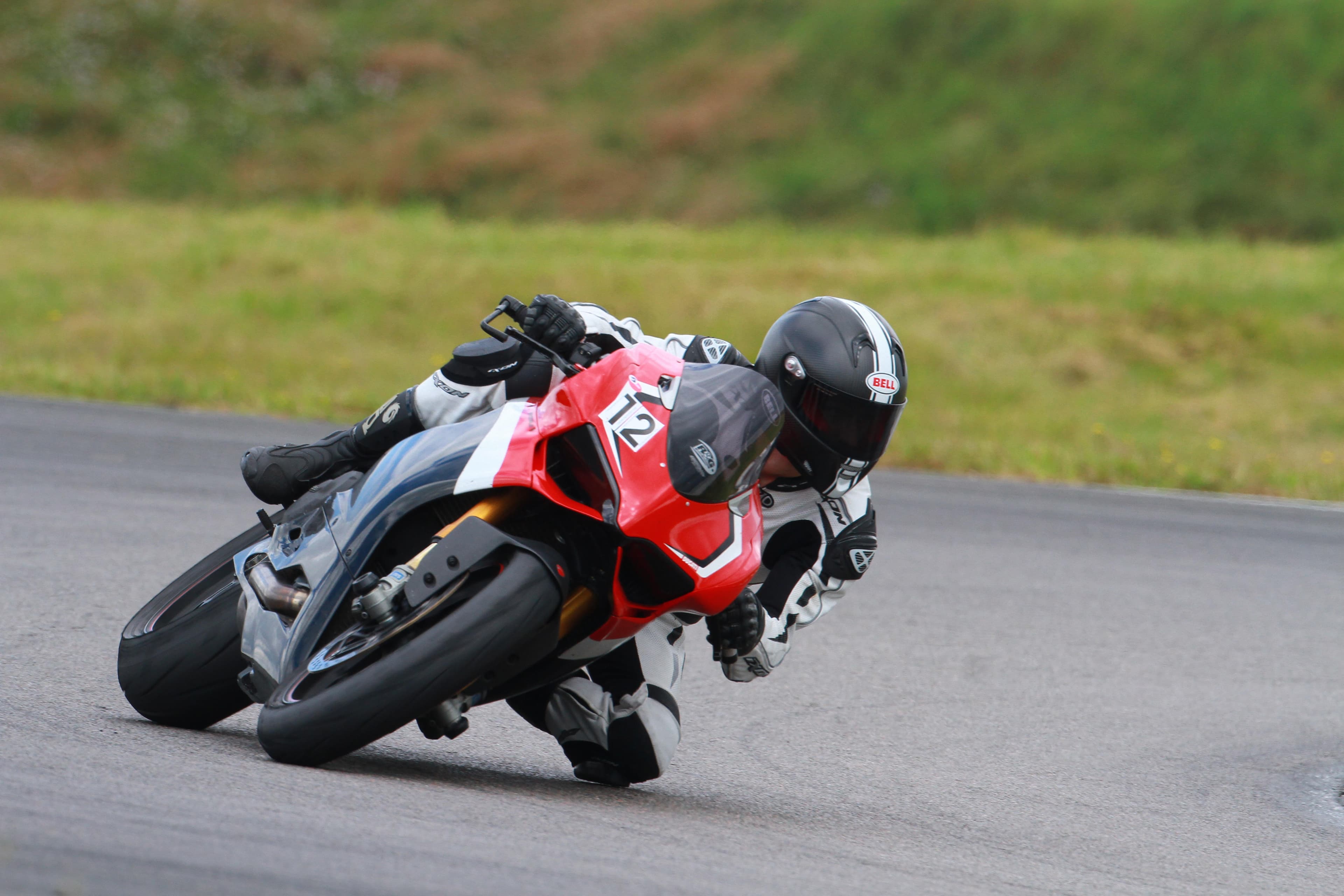 Pilote sur une moto sportive rouge penchée dans un virage, lors d'une journée de roulage sur circuit